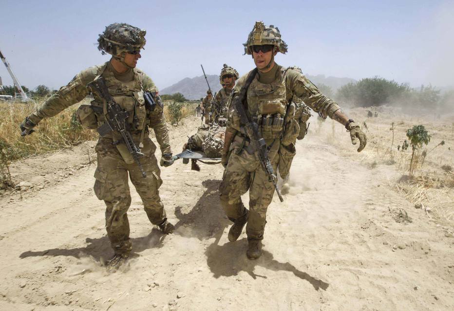 Soldados americanos carregam colega ferido por dispositivo explosivo no Afeganistão; possível acordo de paz poderia resultar na retirada das tropas dos EUA