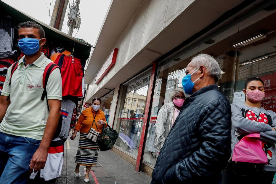 Pessoas com m&aacute;scaras caminham em S&atilde;o Paulo em meio &agrave; pandemia de covid-19