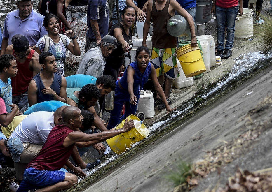 Venezuelanos coletam água do Rio Guaire, um dos mais poluídos do país, em razão do desabastecimento causado pelo apagão que afeta o país há mais de quatro dias