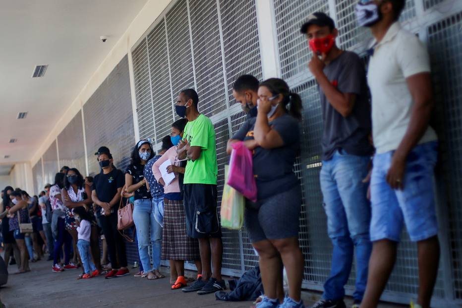 As pessoas esperam na fila em frente a um banco, no bairro Ceilandia, em Brasília.