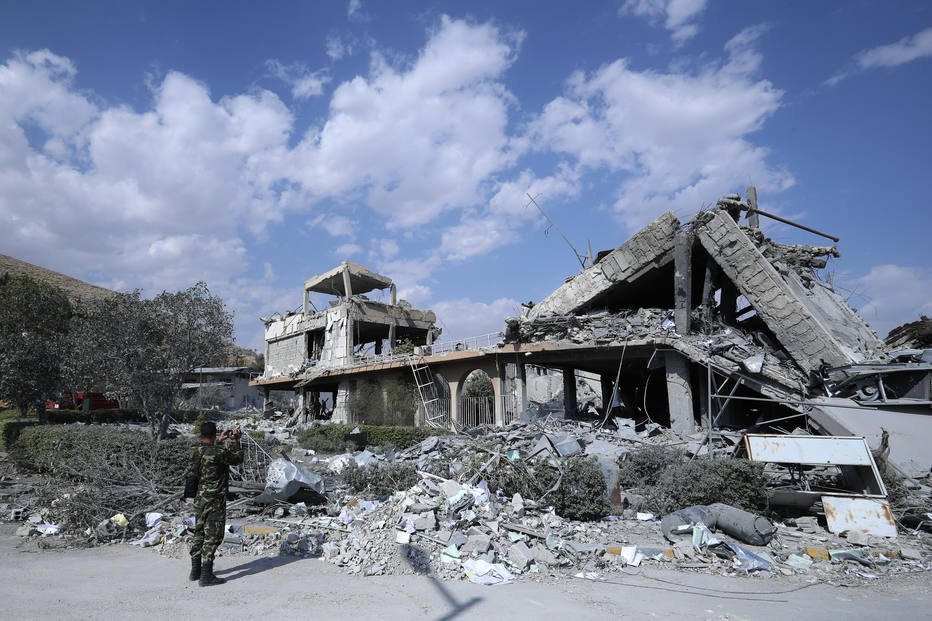 Soldado sírio filma um dos centros de pesquisa destruído por bombardeios da coalizão liderada pelos EUA em Barzeh, perto de Damasco 