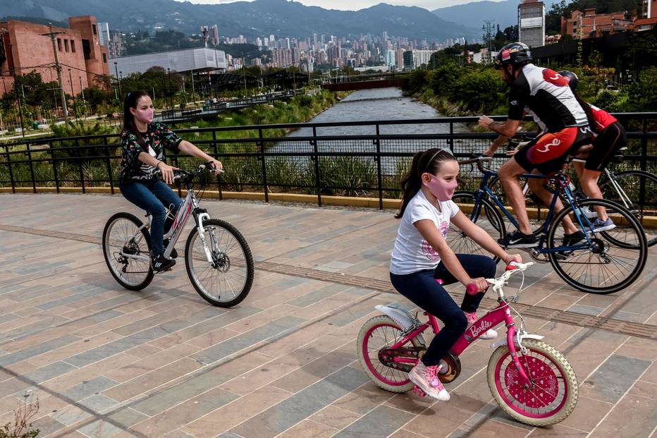 As pessoas usam máscaras faciais enquanto andam de bicicleta em um parque em Medellín, Colômbia.