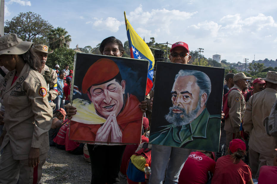 Defensores do presidente venezuelano Nicolás Maduro com imagens de Hugo Chávez e Fidel Castro em comício.