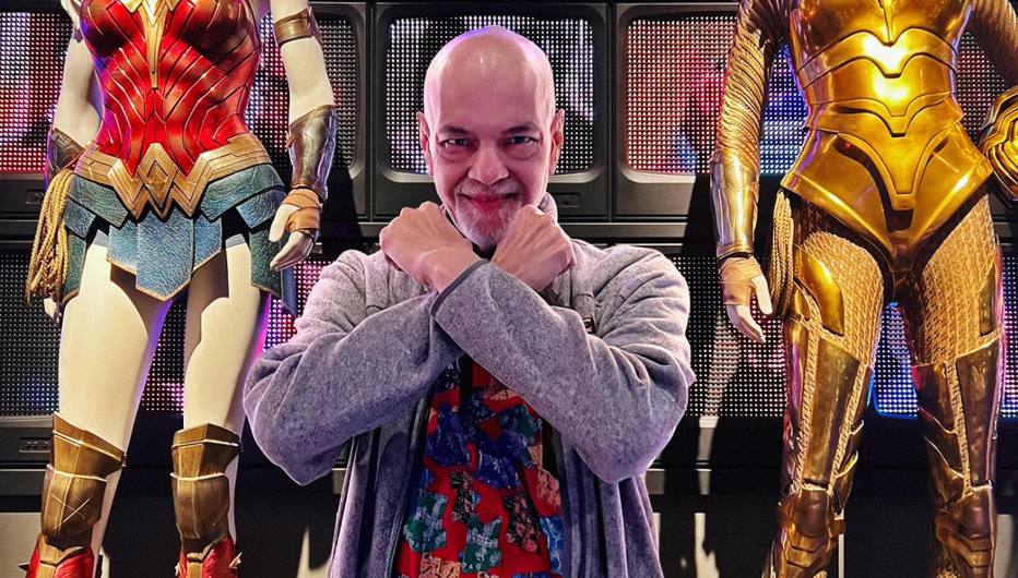 O quadrinista George Pérez em frente a trajes inspirados na Mulher-Maravilha, personagem da DC