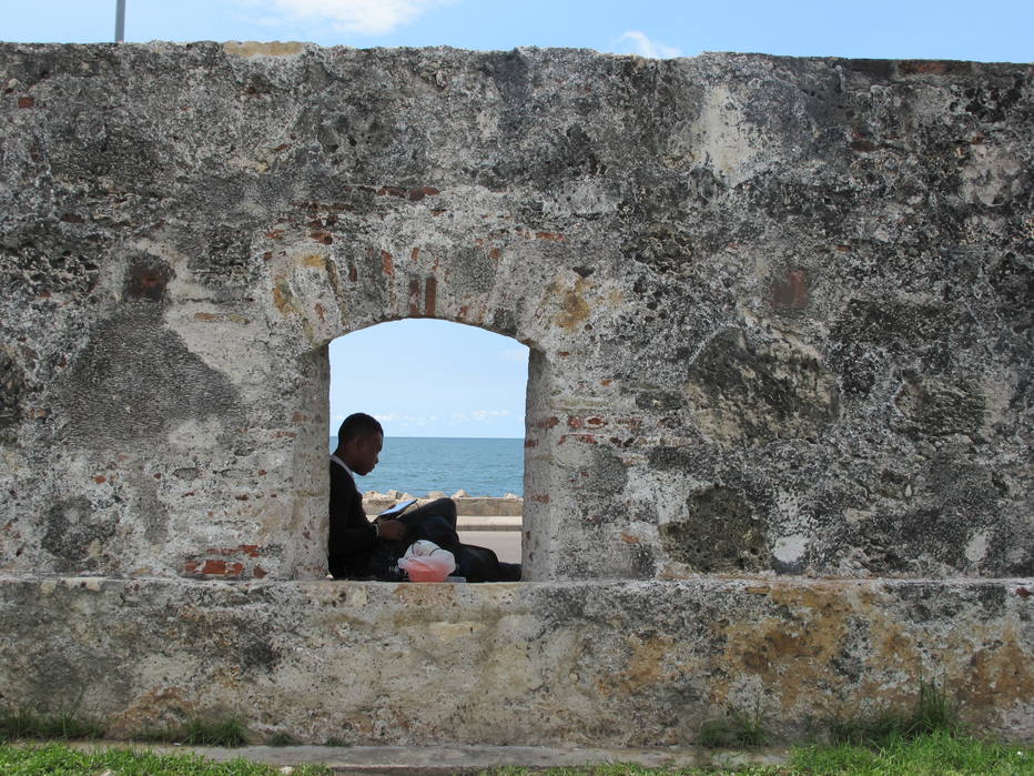 Homem lê livro em janela na muralha da cidade velha de Cartagena