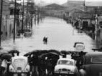 Veículos e pedestres enfrentam enchente na Rua do Gasômetro, no Brás, em São Paulo, SP. 17/3/1966.