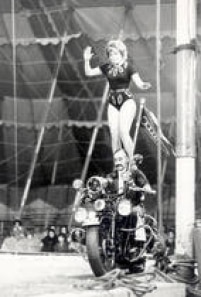 Em pé nos ombros de motociclista, equilibrista apresenta-se no circo Shangai em São Paulo. SP. 10/8/1972. 
