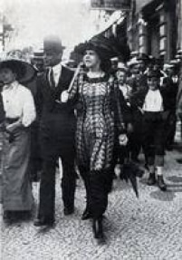 Mulher veste as primeiras <a href='http://https://acervo.estadao.com.br/noticias/acervo,mulheres-de-calca-chocaram-no-inicio-no-seculo-20,12505,0.htm' target='_blank'>calças femininas</a>, as 'jupes- culottes' ou 'saias-calção, em passeio pela Avenida Central no Rio de Janeiro, 1911. Mulheres que se atreviam a desfilar a polêmica peça de roupa pelas ruas corriam o risco de serem perseguidas e hostilizadas. Saiba mais, leia<a href='http://https://acervo.estadao.com.br/noticias/acervo,mulheres-de-calca-chocaram-no-inicio-no-seculo-20,12505,0.htm' target='_blank'> Mulheres de calça chocaram no início no século 20</a><a href='http://https://acervo.estadao.com.br/noticias/acervo,mulheres-de-calca-chocaram-no-inicio-no-seculo-20,12505,0.htm' target='_blank'>.</a>