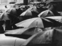 Dezenas de pessoas se protegem com guarda-chuvas no centro da capital paulistana, SP, década de50.