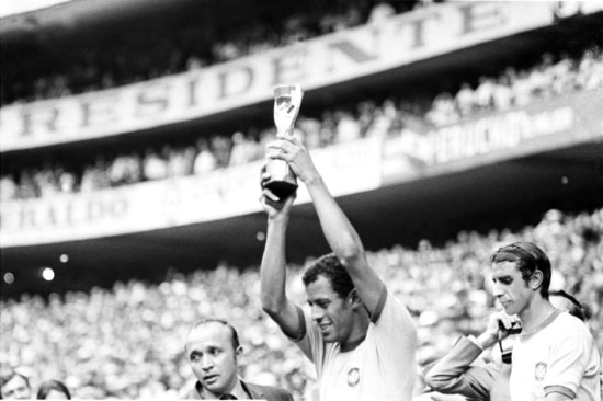 O capitão da Seleção Brasileira, Carlos Alberto Torres, levanta a Taça Jules Rimet, enquanto é observado pelo companheiro Piazza , após o time derrotar a Itália por 4 a 1 no estádio Azteca, na Cidade do México, durante o Campeonato Mundial de Futebol, 21/6/1970.