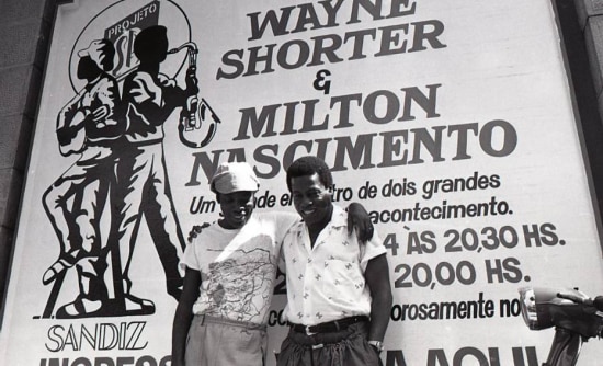Milton Nascimento e o saxofonista americano Wayne Shorter  se abraçam em frente ao cartaz da sua apresentação no Projeto SP, 23/4/1986.