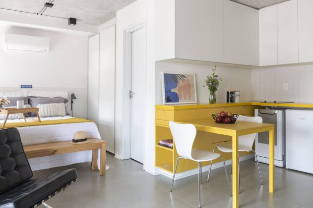 Cris Farhat Vista a partir da sala para quarto e cozinha, com amarelo como cor predominante