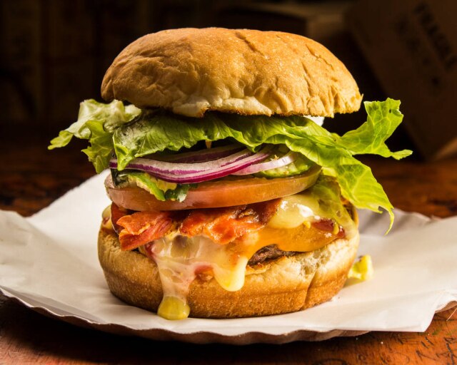 Burger Joint Lazy Boy, do Burger Joint, com queijos colby e cheddar, bacon de costela, alface, tomate, cebola roxa e picles.