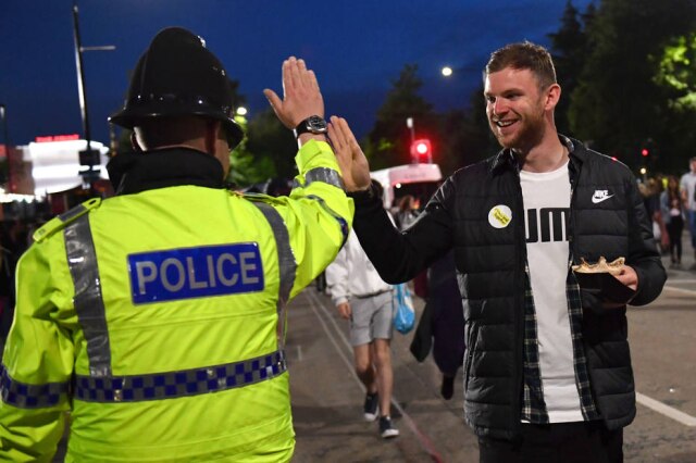 AFP PHOTO/Anthony Devlin Na saída do show One Love Manchester, homem cumprimenta um policial.