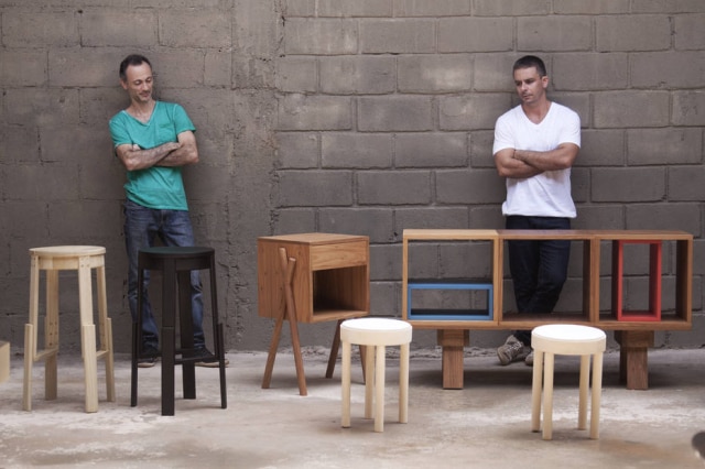 Divulgação Os designers Thiago Antonelli (esq.) e Thelvyo Veiga, com bancos de bar, criado-mudo, banquetas e racks da coleção Jabuticasa