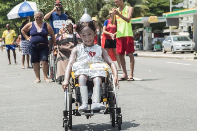 Cristiano Azeredo Heitor fantasiado de Mágico de Oz durante bloco de carnaval inclusivo. Ao fundo, outras crianças com deficiências vêm acompanhadas dos pais.