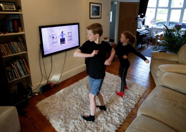 Phil Noble/ Reuters Em quarentena para evitar corobavírus, Alice e Joseph Wilkinson fazem uma aula pelo YouTuben, em Manchester, na Inglaterra