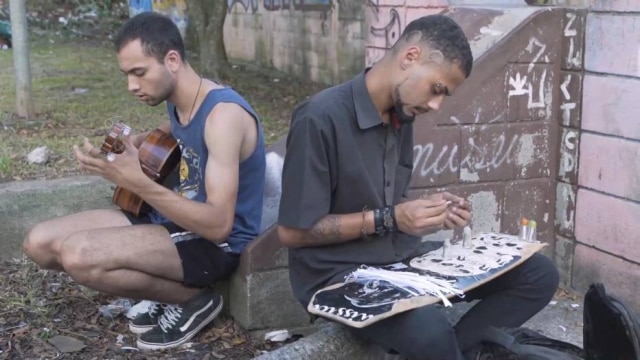 Reprodução de 'Lança' (2018) / Divulgação Antonio Guerra (à direita) preparando as poesias para colocar nos frascos usados de lança-perfume. Poeta diz se sentir feliz em ajudar pessoas a se conscientizarem sobre a redução de danos da droga.