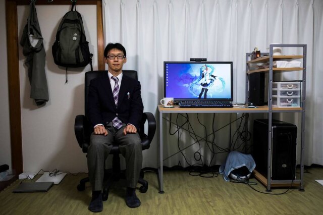 Behrouz Mehri / AFP Akihiko Kondo posa em sua casa com a figura virtual com quem se 'casou'.