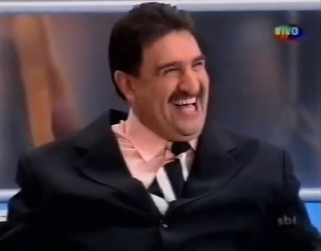 Reprodução de 'Hebe' (2004) / SBT O apresentador Ratinho dá risada durante momento do programa 'Hebe', em 2004.
