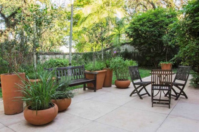 Zeca Wittner/Estadão No jardim assinado pela Jardineiro Fiel, banco e mesa usados na hora do chá, feito com ervas colhidas dos vasos de barro, onde também são plantados temperos