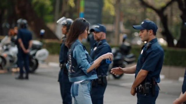 Reprodução/ Comercial Pepsi Modelo entrega uma lata de Pepsi ao policial e a multidão vibra