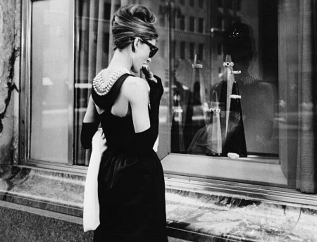 Paramount/ Divulgação Cena icônica de 'Bonequinha de Luxo', onde a personagem de Audrey Hepburn come um croissant na frente da loja da Tiffany's