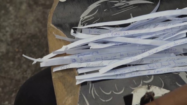 Reprodução de 'Lança' (2019) / Divulgação Poesias são escritas em tiras de papel.