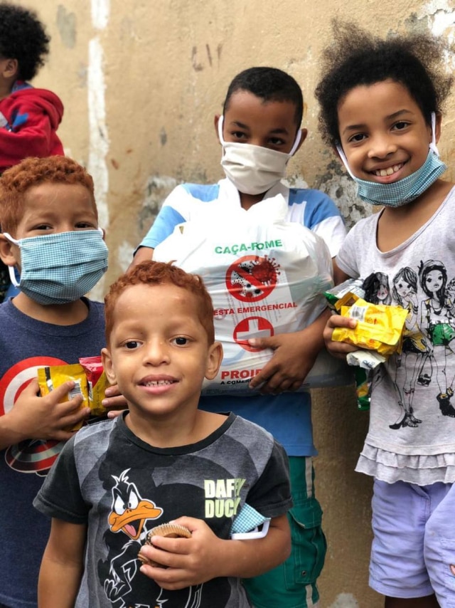 arquivo pessoal Vestidas com máscaras laranja, símbolo do projeto 'Caça-Fome', crianças recebem alimentos durante pandemia