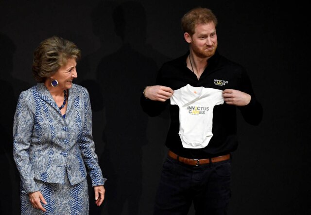 Piroschka Van De Wouw/Reuters Príncipe Harry ao ganhar uma roupa de bebê como presente para o filho recém-nascido.