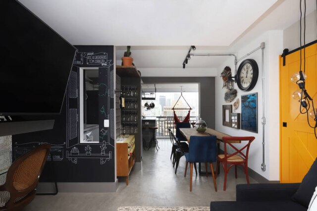 Mariana Orsi A vista do 14º andar pode ser apreciada da sala de estar, graças à integração da varanda. A parede do home office na sala tem frases desenhadas, criadas pelo casal