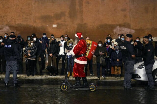 RICCARDO ANTIMIANI/ ANSA Homem vestido de Papai Noel passeia de patinete pelas ruas de Roma.