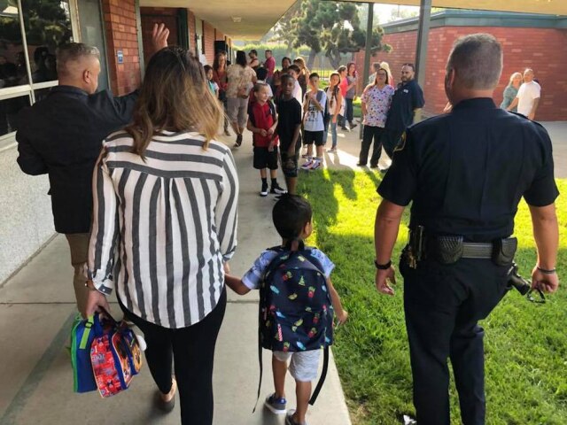 Facebook/PomonaPD Policiais escoltaram menino que perdeu o pai, que era policial, até a escola.