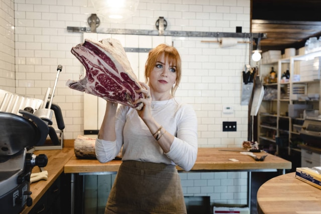 Ryan Dearth/The New York Times A açougueira segura costelas que tinha acabado de cortar. A carne marmorizada é uma das marcas de seu açougue