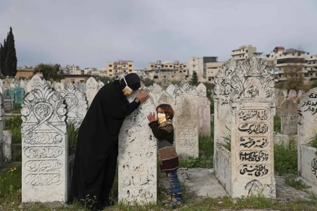 Aaref Watad / AFP Mãe e filha visitam túmulo de um parente em cemitério na cidade de Ariha, no norte da província de Idlib, na Síria