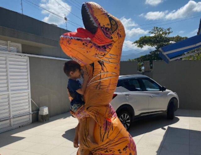 Juan Lambert / Arquivo Pessoal O médico Juan Lambert, fantasiado de dinossauro, abraçado com o filho, Luca