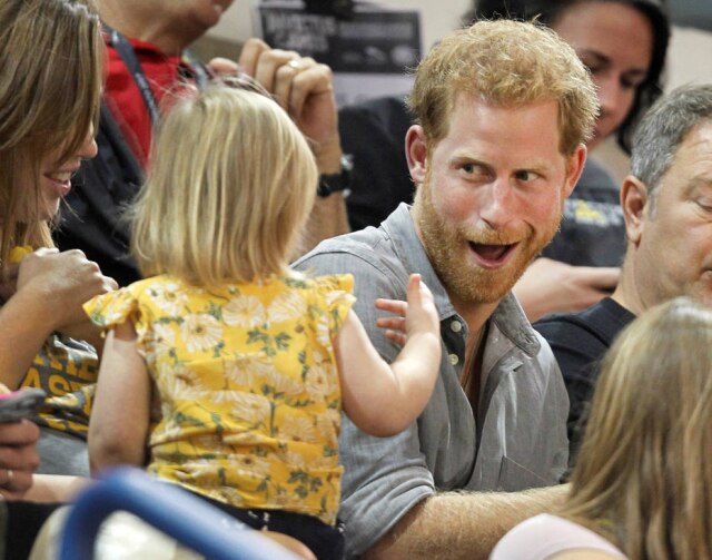REUTERS/Fred Thornhill Príncipe Harry brincando com a menina na arquibancada.