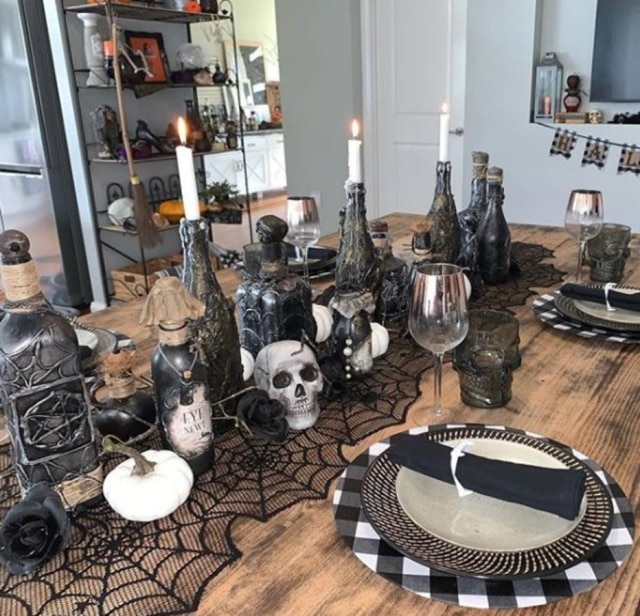 Instagram/@liveitlikelisa Teias de aranha servem como arranjo de mesa central que sustentam velas, caveiras e garrafas que imitam poções