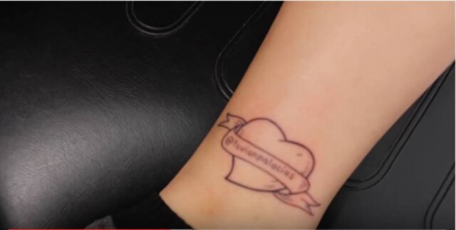 https://www.youtube.com/watch?v=WqByNgyqglA&t=70s Desenho feito na perna da jovem carrega nome de usuário do Twitter de seu amigo