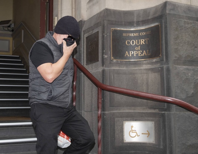 Ellen Smith / AAP Image via AP David Hingst cobre seu rosto ao deixar a Corte de Apelação em Melbourne, na Austrália, na última sexta-feira, 29 de março.