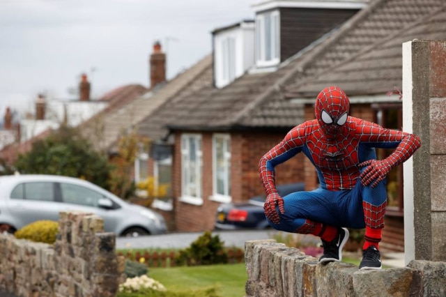 Phil Noble / Reuters O professor Jason Baird vestido como Homem-Aranha durante período de quarentena na cidade de Stockport, na Inglaterra.
