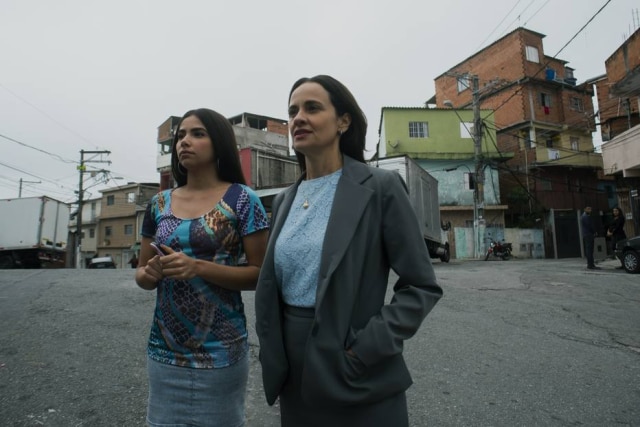 Rafael Morse/Netflix Rita e a pastora Sueli (Fernanda Viacava) olhando para a igreja evangélica da comunidade. Congregação existe e faz parte do dia a dia dos moradores da favela do Jaguaré.
