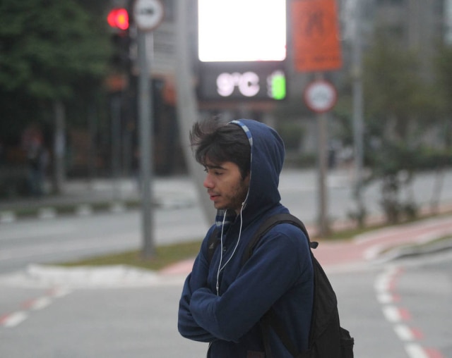 WERTHER SANTANA/ESTADÃO Jovem caminha na Vila Olimpía na manhã desta sexta-feira, quando termômetros marcavam 9°C