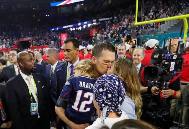 Kevin C. Cox/ Afp Gisele Bündchen beija o marido Tom Brady que segura a filha do casal Vivian Lake no colo